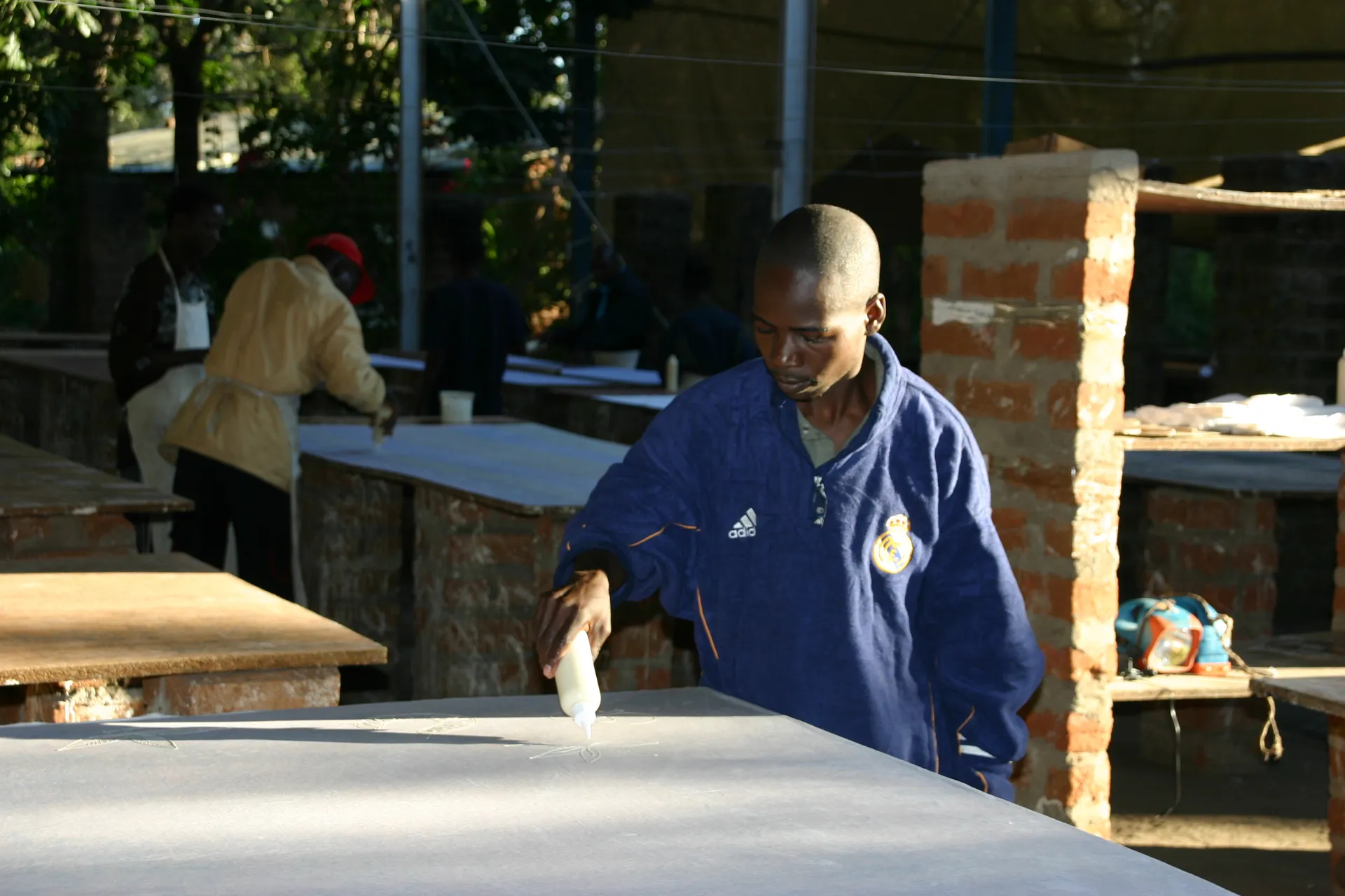 Arbeider bij <i>Tribal Textiles</i> bezig met het tekenen van een rozet [Mfuwe]
