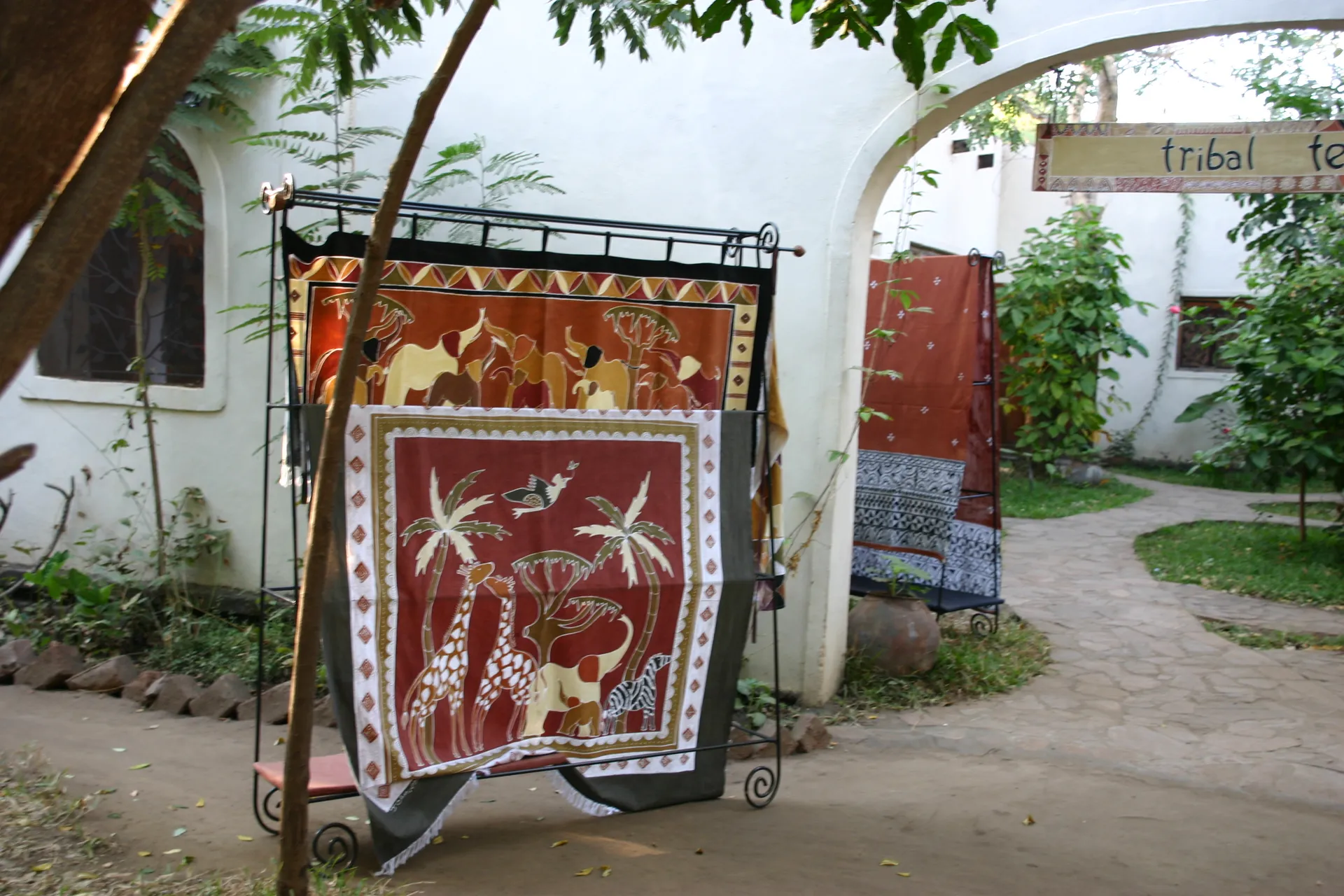 Bij de winkel hangen de kleurige producten van <i>Tribal Textiles</i> gereed voor de verkoop [Mfuwe]