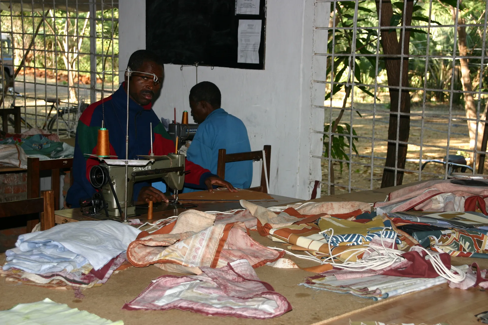 De geverfde lappen worden met de naaimachine verwerkt tot tassen, slopen e.d. [<i>Tribal Textiles</i>, Mfuwe]