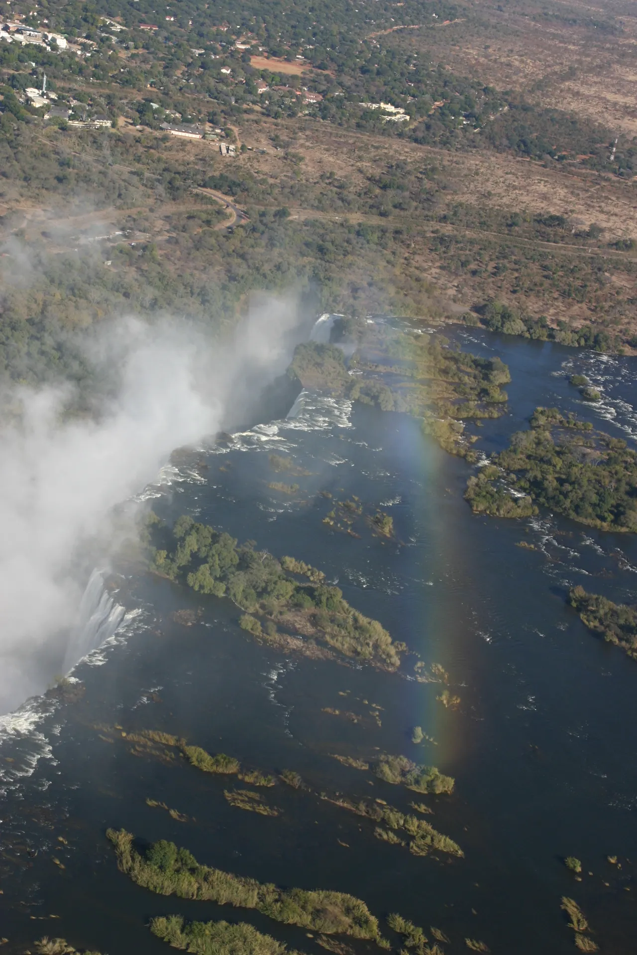 De watervallen met in de verte de plaats Victoria Falls in Zimbabwe