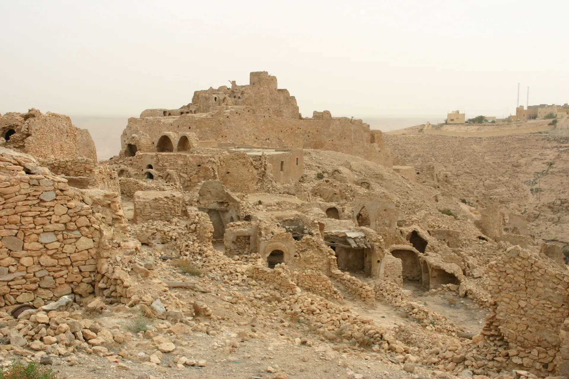 Graanburcht van Nalut, in de verte op de heuvel, op de voorgrond de huisjes van de verlaten Berber-nederzetting