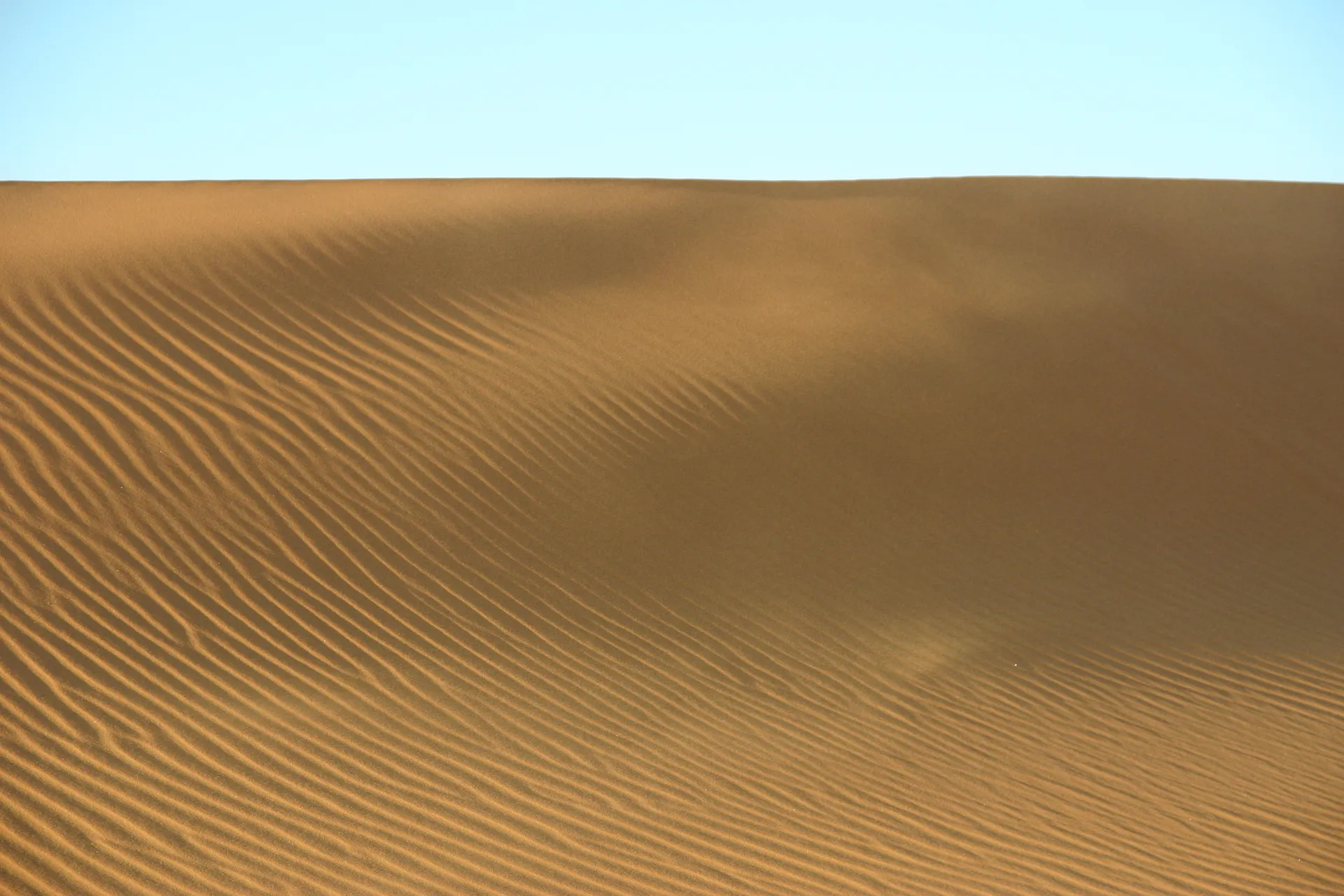 Bijna onzichtbaar stuift het zand van rechts naar links over het duin [Ouan Kasa zandzee]