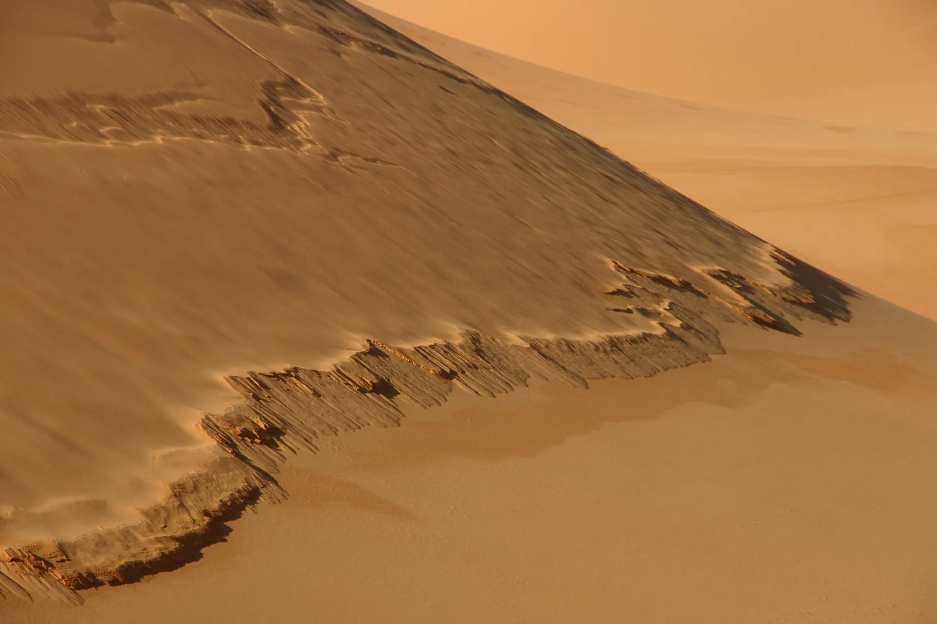 Door de zwaartekracht zakt het opgestuwde zand over grote breedte in een trage stroom weer omlaag [Ouan Kasa zandzee]
