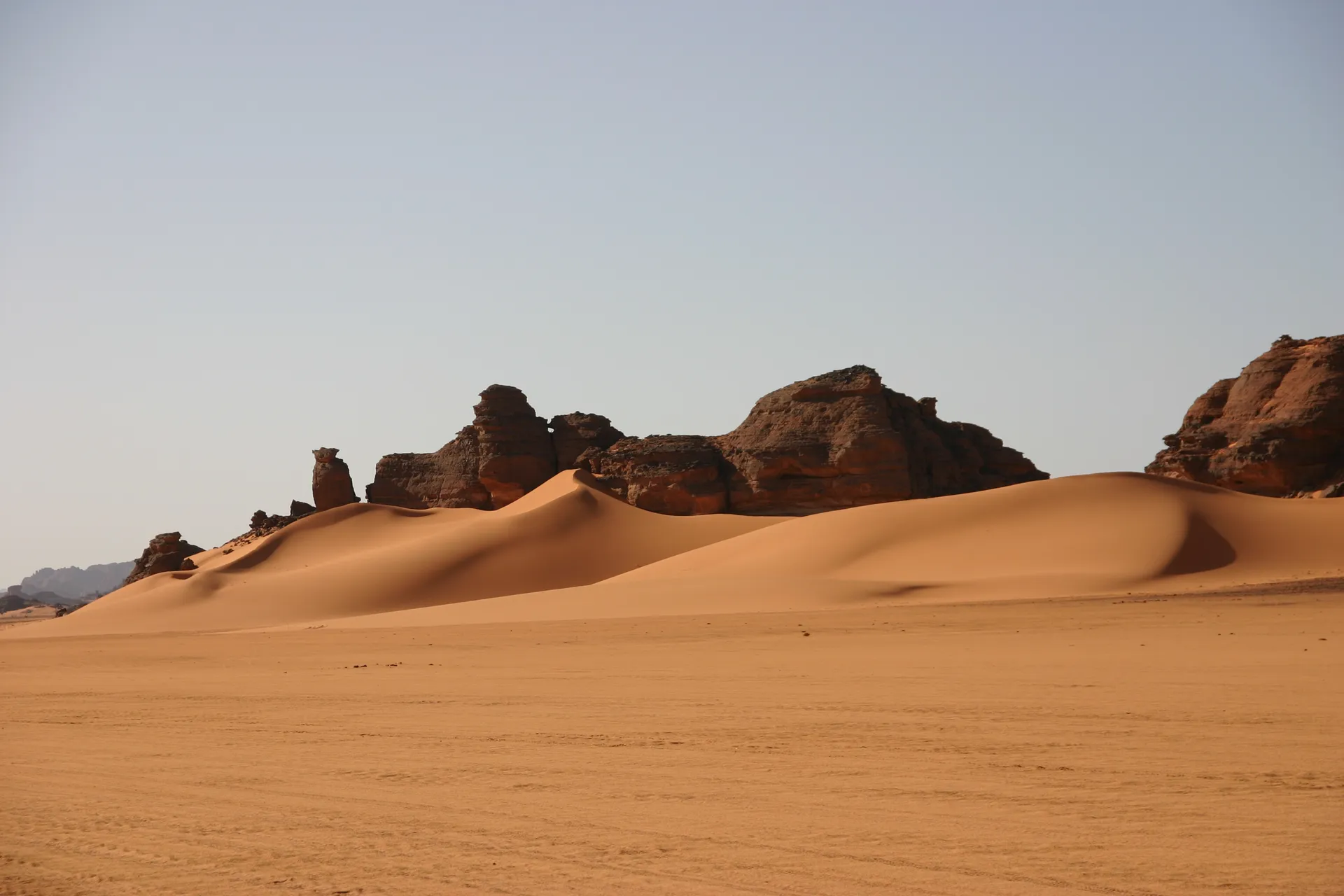 Hoog is het zand opgewaaid tegen de rotsen [Akakus gebergte]