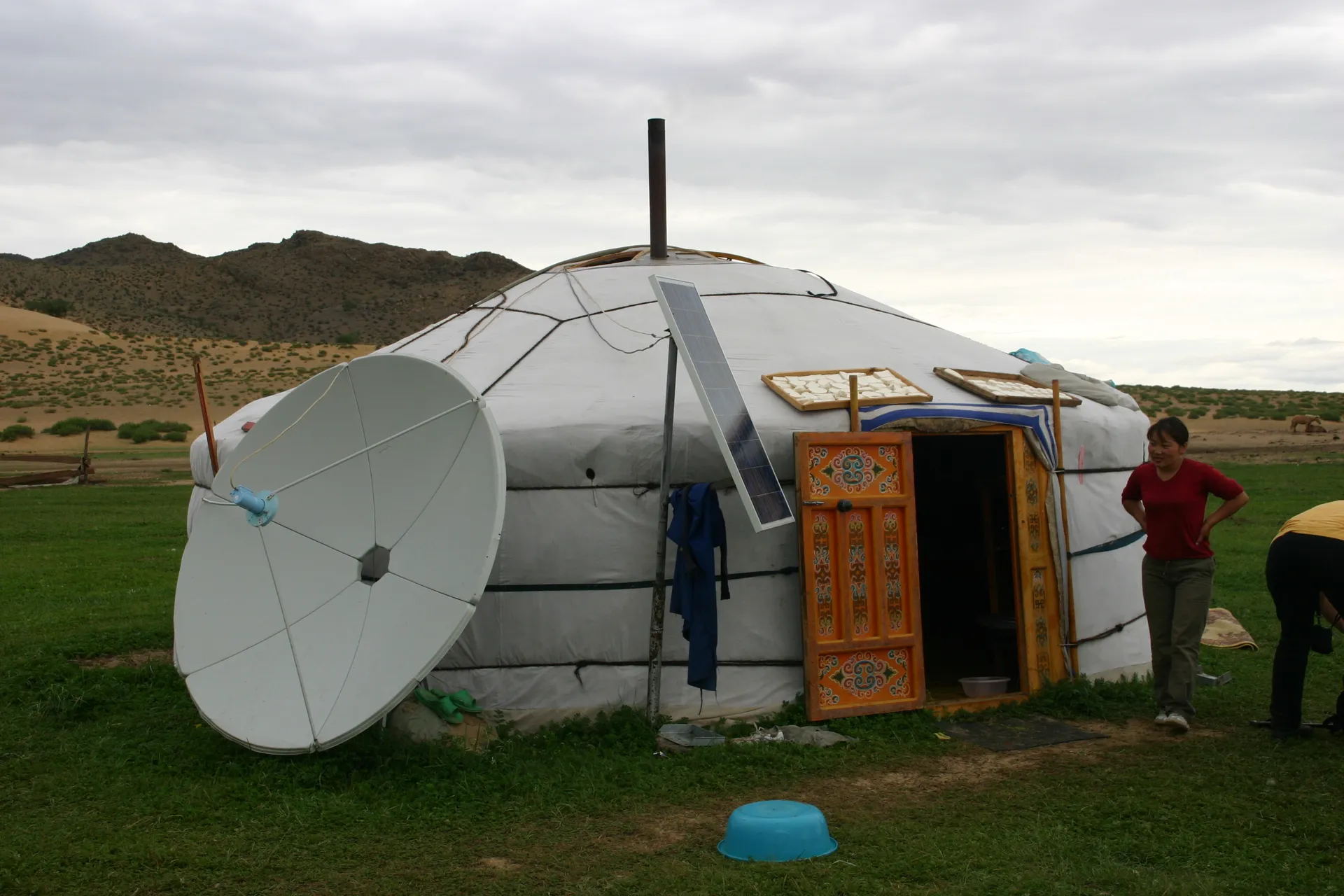 Buiten zijn de moderne ontwikkelingen te zien: schotelontvanger en zonnepaneel, op de tent ligt <i>aaruul</i>-kaas te drogen [omgeving Khogno Khan]